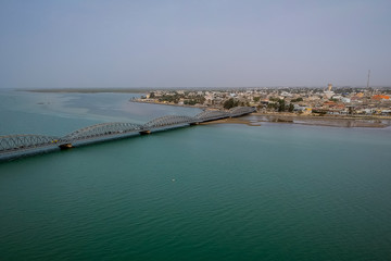 Aerial photo of Senegal river in Sant Louis, Senegal, with the Faidherbe bridge seen connecting the new part of the city on an overcast day.