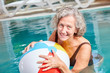 Happy senior woman with ball in the pool