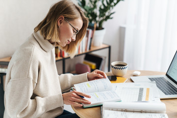 Poster - Photo of woman making notes in exercise book and using laptop