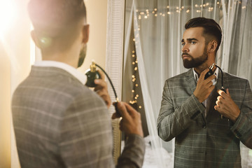 Wall Mural - Handsome bearded man is using atomizer nozzle with perfume