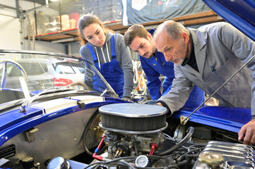 Instructor with trainees working on car engine