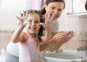 Cheerful kid washing hands and showing soapy palms