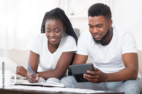 Fotomural Millennial afro couple managing family budget together, calculating spents