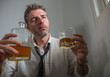 © TheVisualsYouNeed - portrait of 30s to 40s alcoholic  man in lose necktie drinking desperate holding whiskey glass thoughtful drunk and depressed completely wasted in alcohol addiction concept