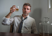 Portrait Of 30s To 40s Alcoholic  Man In Lose Necktie Drinking Desperate Holding Whiskey Glass Thoughtful Drunk And Depressed Completely Wasted In Alcohol Addiction Concept