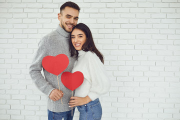 Wall Mural - Concert Valentine's Day. Young couple with hearts in hands on a white brick background