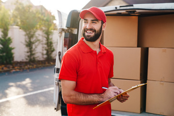 Poster - Image of smiling delivery man holding clipboard and writing