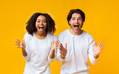 Wall Mural - Shocked Multiracial Couple Exclaiming With Amazement And Emotionally Gesturing With Hands