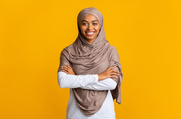 Wall Mural - Portrait of black muslim girl in hijab over yellow studio background
