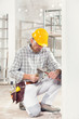 © guerrieroale - Builder kneeling using a chisel and mallet