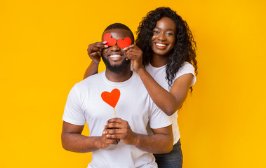 Wall Mural - Smiling black woman closing her man eyes with valentine cards