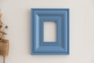 blue vintage wooden picture frame on white concrete wall. blank timber art frame.