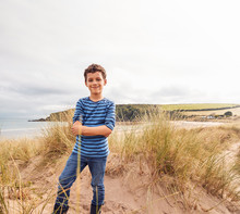 Portrait Of Boy Exploring Sand Dunes On Winter Beach Vacation