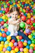 © moodboard - Young girl in ball pit throwing colored balls