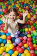 © moodboard - Young girl in ball pit throwing colored balls
