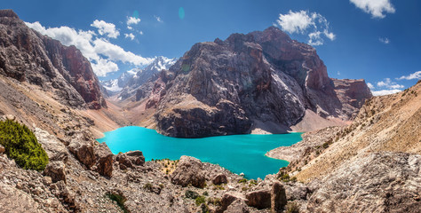 Fototapete - Tajikistan, view from the rock to Great Allo lake with narrow valley among Fan mountains. Sunny and beautiful day for hike on Fann mountains.