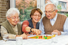 Elderly Couple And Daughter Playing Board Game