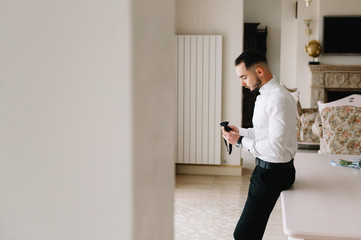 Serious man buttoning his shirt in optimistic mood, getting ready for work