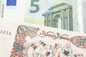 Wall Mural - A beige, two hundred Algerian dinar bill with a red, European Union five euro bank note close up in macro