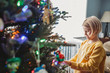 © Cavan Images - Girl decorating Christmas Tree with colored lights