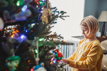 Girl Decorating Christmas Tree With Colored Lights