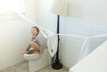Boy Making Mess In Bathroom With Toilet Paper Hung On Wall