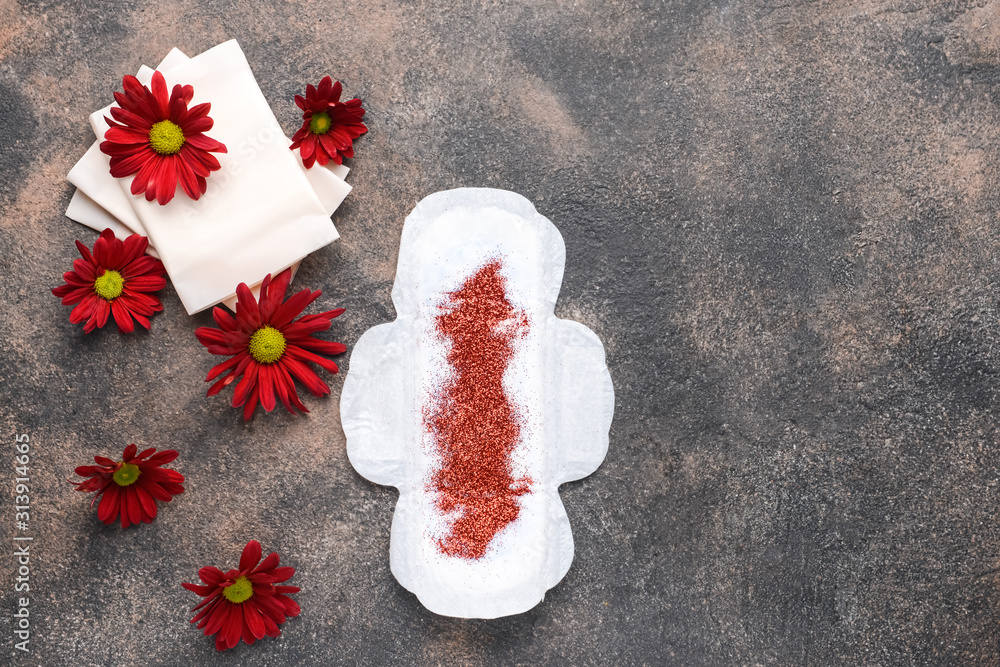 Menstrual pads with flowers and glitter on grey background. Menstruation concept