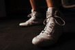 © Cavan Images - Closeup of white boxing shoes on dark background during workout.