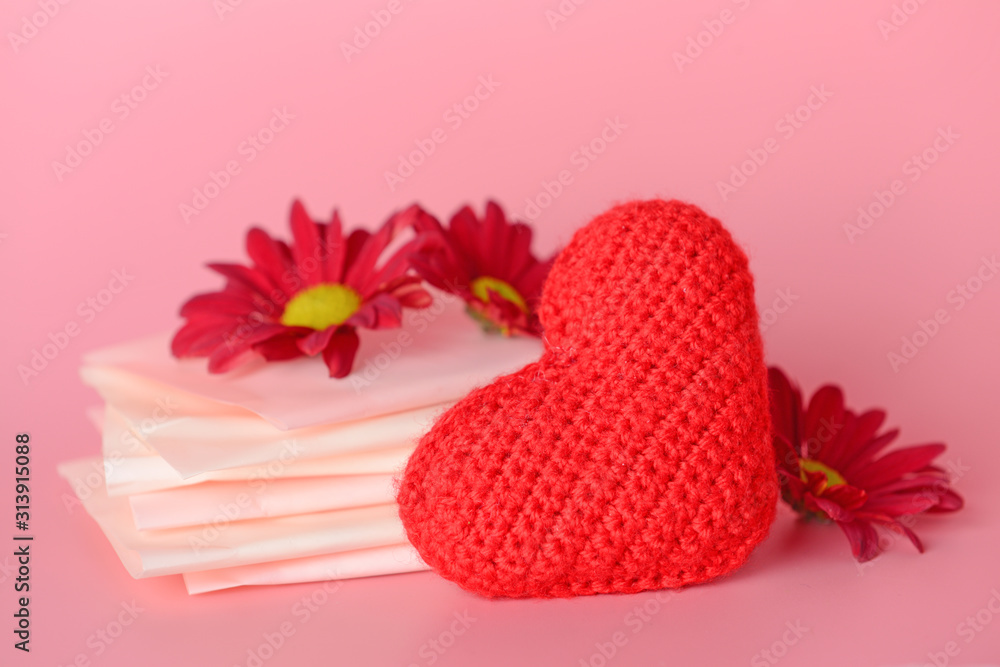 Menstrual pads with red heart and flowers on color background. Menstruation concept
