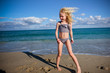 © Cavan Images - girl smiling standing on the beach wind blowing hair blue skies