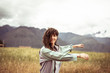 © Cavan Images - Girl with wild curly hair spins and smiles in field with mountians