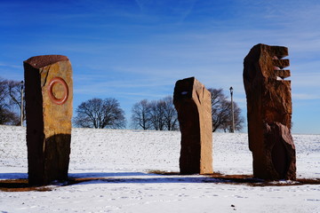 3 old vintage red stone statue structures standing at a park in Milwaukee, Wisconsin. 