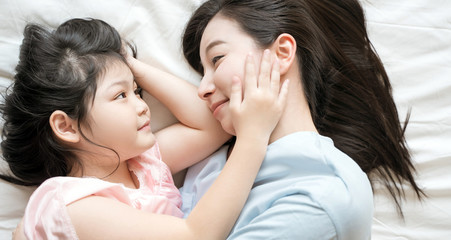  Mother and daughter child girl spending time together in the bedroom Look at each other and smiling .Happy Asian family