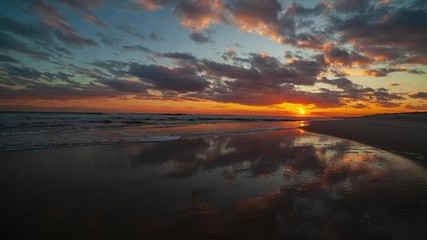 Wall Mural - Clouds moving across the sky, reflecting in ocean waves as the tide rises. Time Lapse