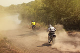 Fototapeta Konie - Two motorcyclists catching up with each other in the dust, view from the back, motocross sport competition