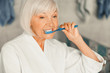 © Yakobchuk Olena - Senior lady brushing teeth in the morning