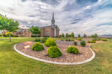 Scenic View Of Church With White Steeple And Landscaped Yard On A Cloudy Day
