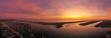 Wide Panoramic View Of Golden Hour And Pink Sunset Over Newport Beach Harbor In Orange County California With Reflection And Boats In The Water Below.
