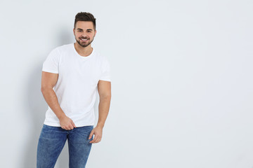 Wall Mural - Young man in stylish jeans on light background. Space for text