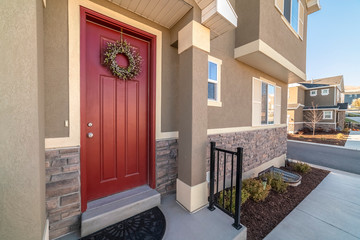 Wall Mural - Colourful red entrance door with wreath near sunset