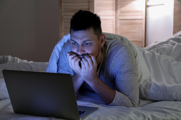 Wall Mural - Emotional man with laptop in bed at night