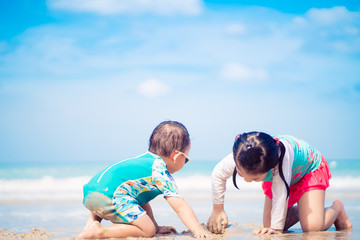 Wall Mural - 5.10 years old Little asian girl playing on the beach with her 2.9 year old baby brother.Family with children at the beach. EF, Motor skills development.Sibling on Vacation summer and relax concept.