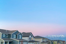Exterior Of Homes And Mountain With Snowy Peak Against Cloudy Blue Sky At Sunset