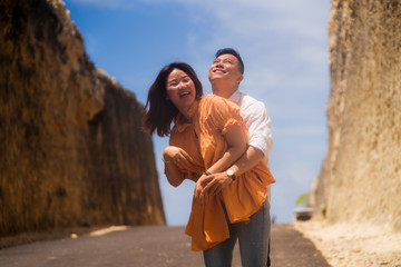 young happy and beautiful Asian Chinese couple in love enjoying outdoors romantic journey walking in cliff rock road exploring the landscape together in holidays travel adventure