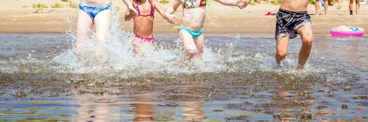 Wall Mural - group of beautiful children runs in a wig and splashes water on a summer hot sunny day