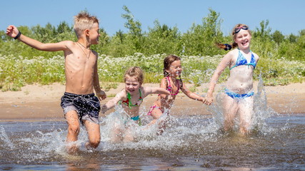 group of beautiful children runs in a wig and splashes water on a summer hot sunny day