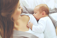 A Woman Is Breastfeeding A Baby. 