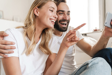 Sticker - Cheerful beautiful young couple sitting at the couch