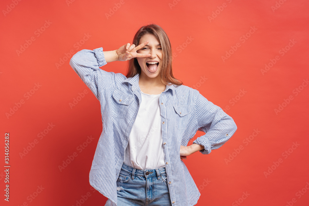 Funny, carefree girl having fun isolated on a red background with open mouth - obrazy, fototapety, plakaty 