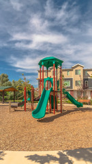 Wall Mural - Vertical frame Park with playground and pavilion against townhouses and blue sky with clouds